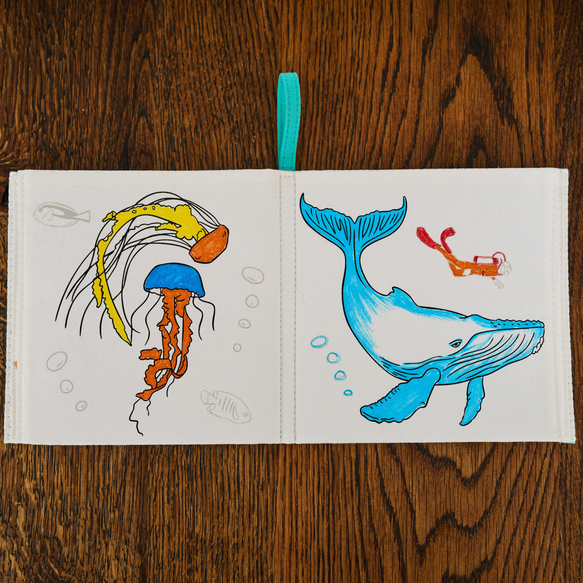 Open book with illustrations of a jellyfish and a whale on a wooden surface